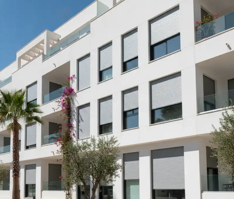 Fachada de edificio con persianas uniformes en Chiclana de la Frontera